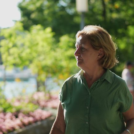Older woman walking outdoors on a sunny day, smiling and confident, representing health, energy, and purpose in retirement