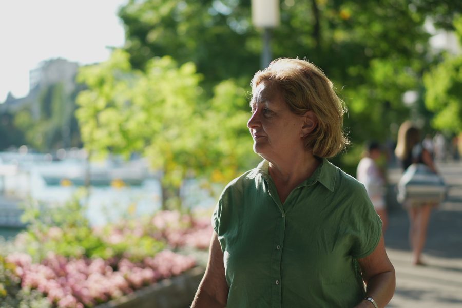 Older woman walking outdoors on a sunny day, smiling and confident, representing health, energy, and purpose in retirement