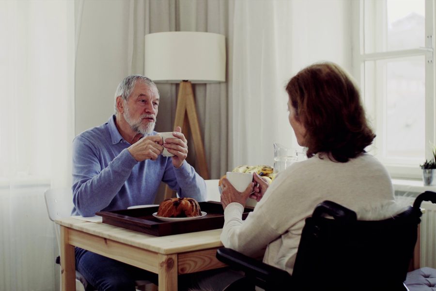 Retired couple at different life stages, with one partner dressed for work and the other relaxing at home, highlighting the tension and transition of mismatched retirement timing