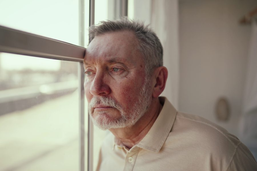 Retired person sitting near a window, looking reflective and quiet, symbolizing emotional transition and the sense of loss that can come with retirement