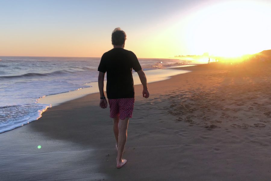 Retired man walking alone on beach, reflecting on how quickly summer is passing by