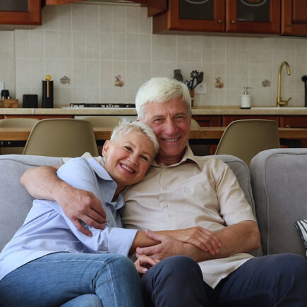 Retired couple laughing together on their couch after resolving a disagreement.