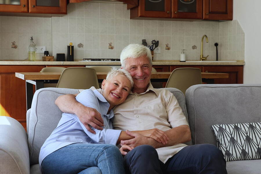 Retired couple laughing together on their couch after resolving a disagreement.