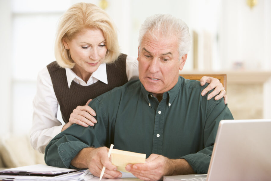 Retired couple reviewing expenses at home to reduce unnecessary spending.